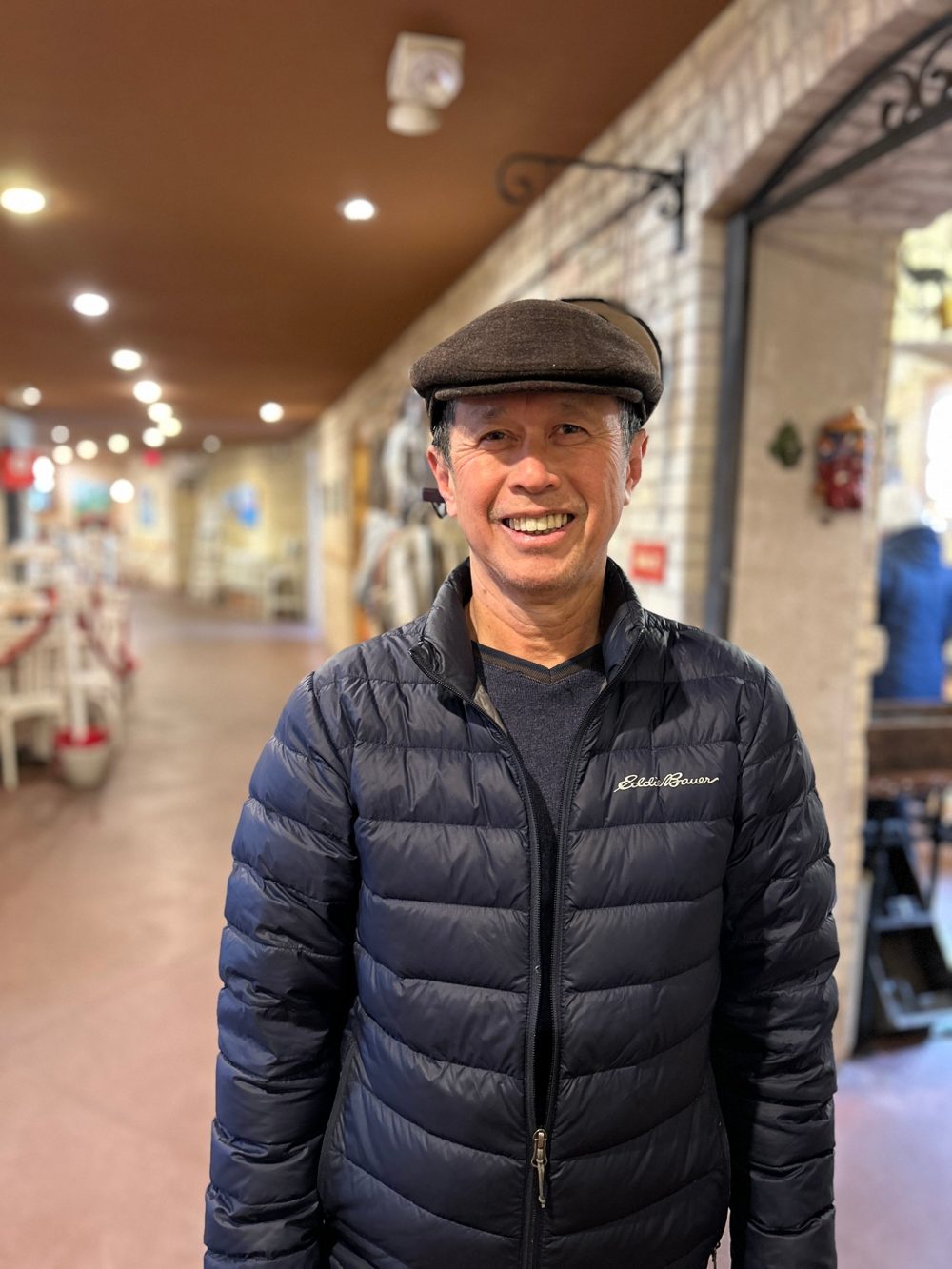 Alan Lim smiling, wearing a flat cap and a navy jacket
